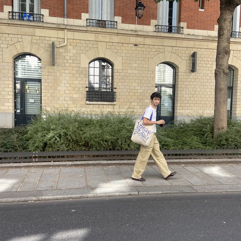 Alon Katz, un jeune peintre parisien qui marche dans la rue avec le pantalon beige en coton recyclé LATER