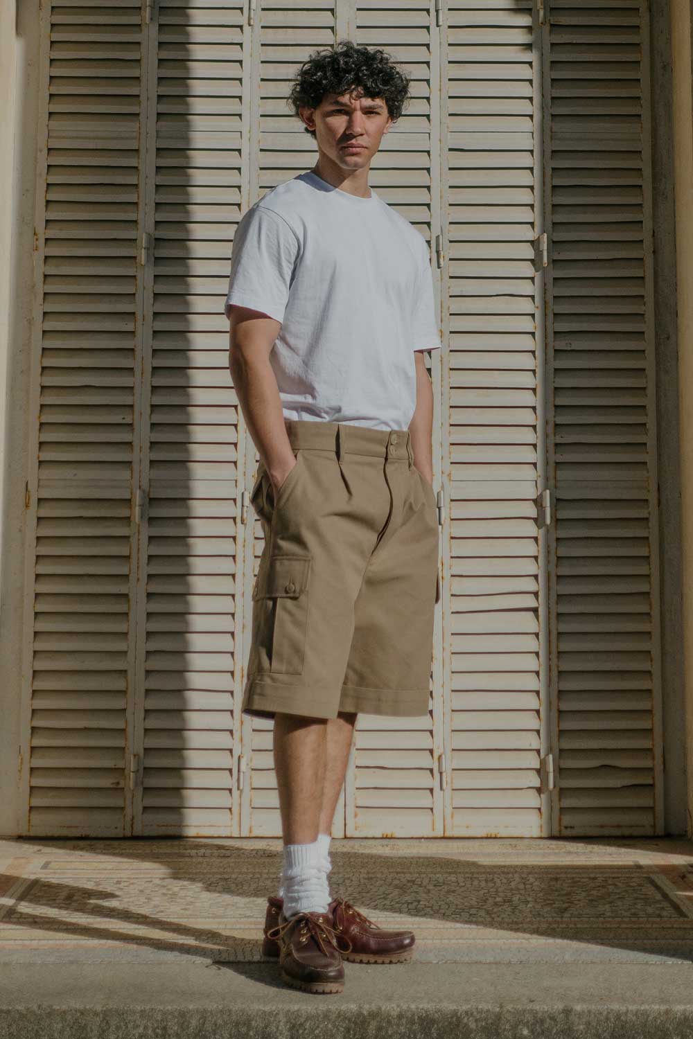 Homme de face de plein pied portant le bermuda cargo beige de LATER...